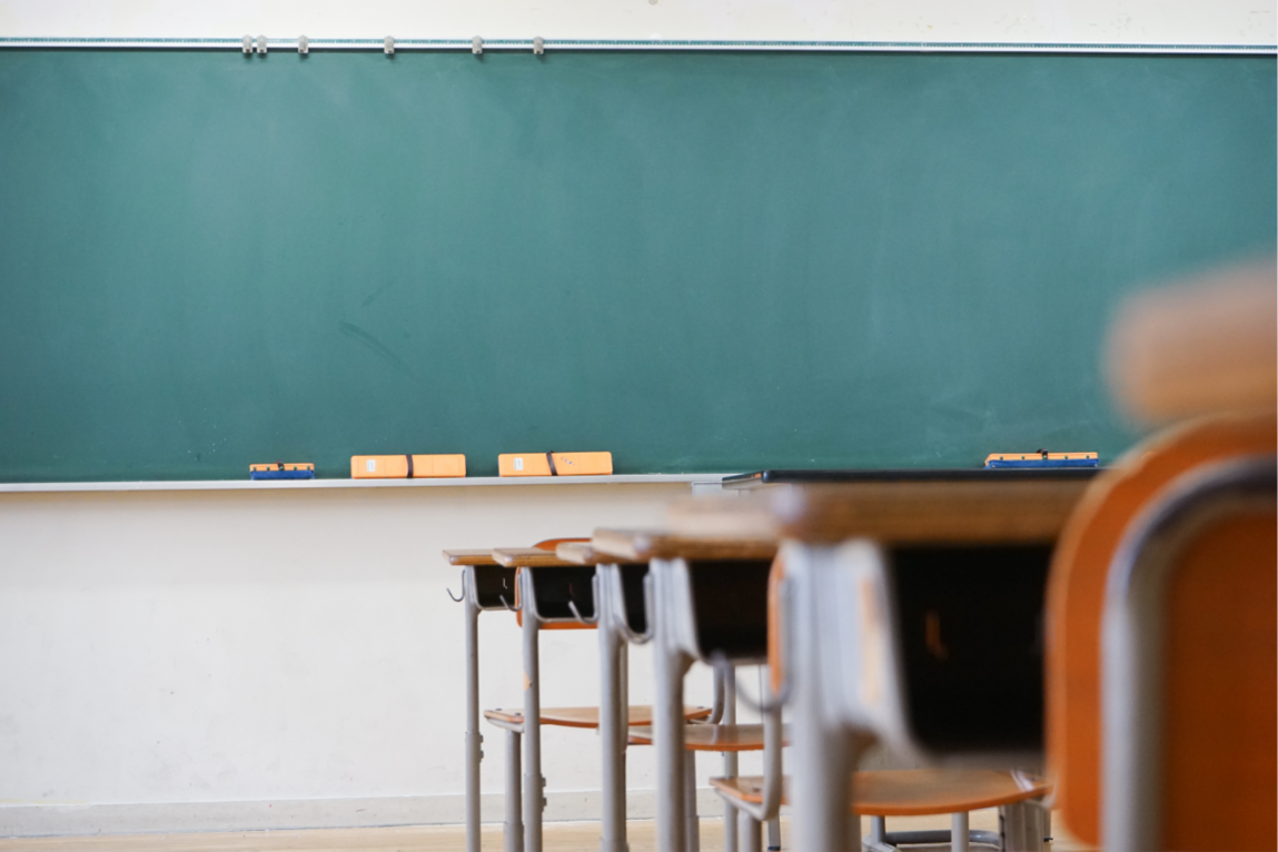 Image d'une classe avec table en bois et tableau à craie vert